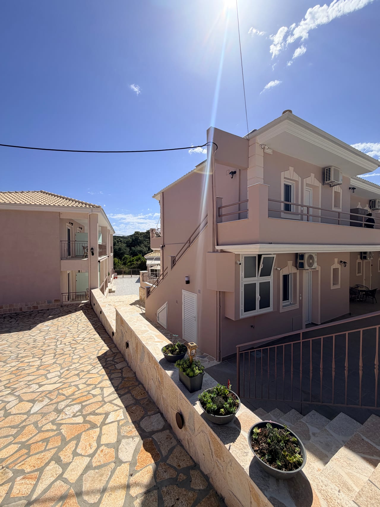 Πλευρική όψη του Breeze Hotel με πέτρινη αυλή και φωτεινή πρόσοψη