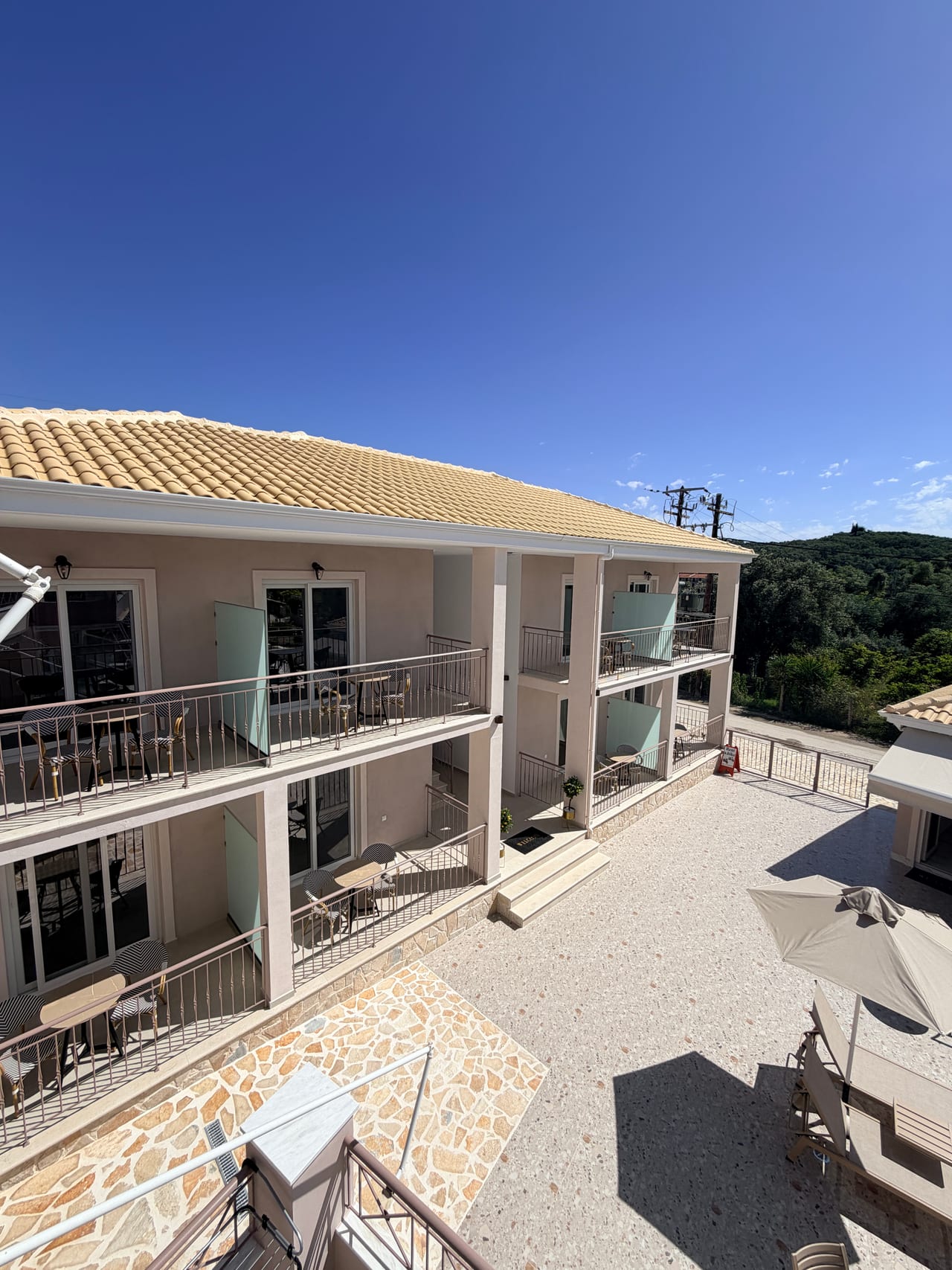 Η πρόσοψη του Breeze Hotel με μπαλκόνια και πέτρινη αυλή