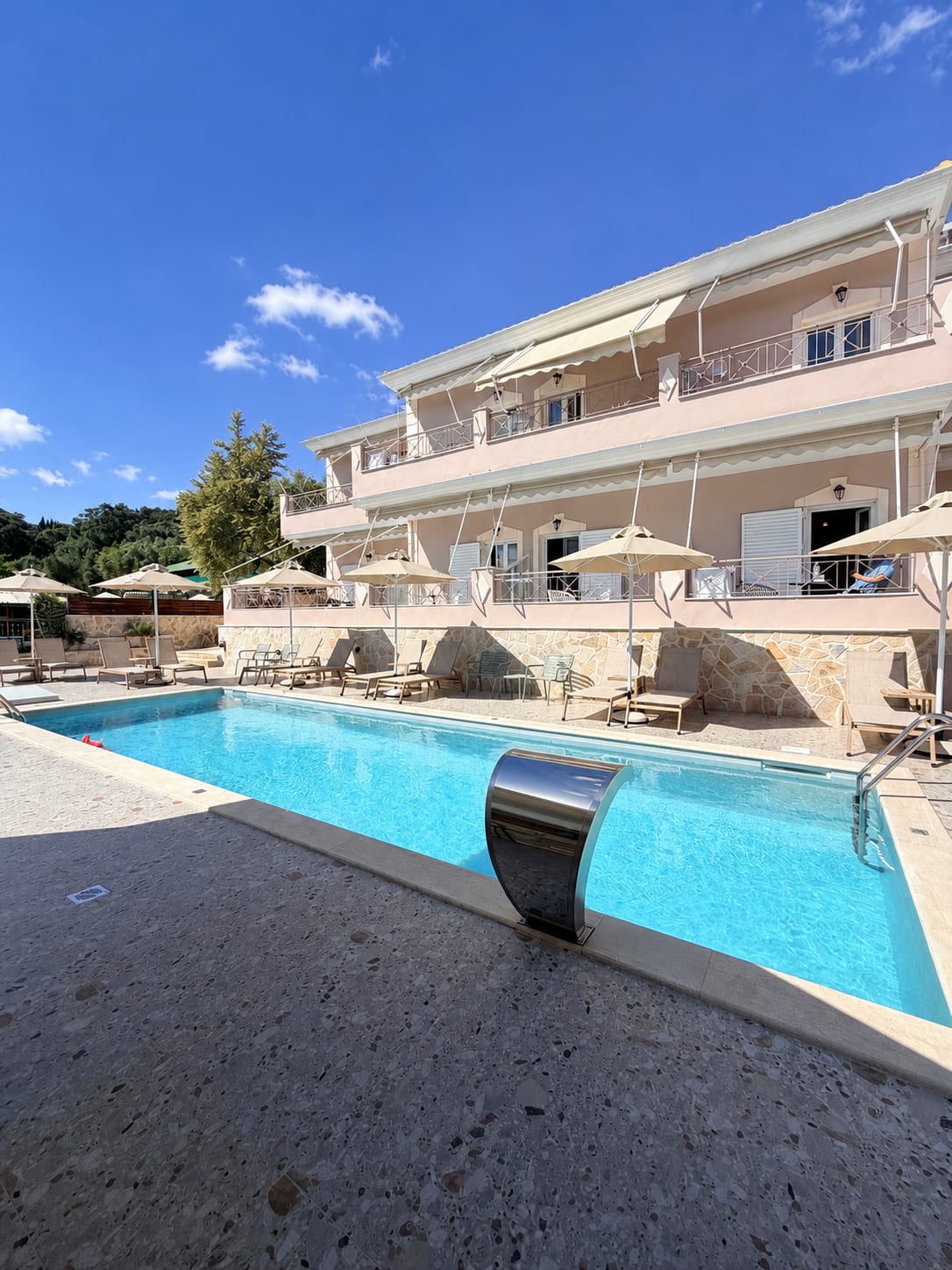 Η πισίνα του Breeze Hotel με θέα στον ελαιώνα και τον γαλάζιο ουρανό της Πάργας